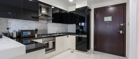 Una cocina moderna con armarios negros, una campana extractora de acero inoxidable, un microondas y un horno empotrado.