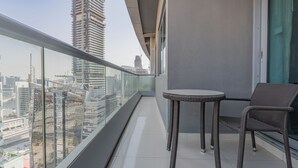 A balcony with a view of a cityscape, featuring tall buildings and a glass railing. - DAMAC Maison Mall Residences - Downtown (Dubai)