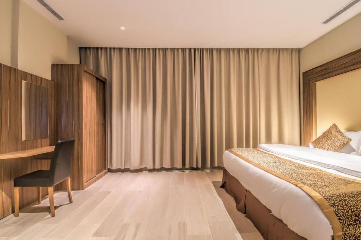 A hotel room with a bed, a desk, and a chair.