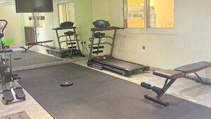 A gym with exercise equipment, a treadmill, and a bench. - Tiara Quraish (Jeddah)