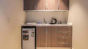A compact kitchen with wooden cabinets, a built-in sink, and a small refrigerator. - Tiara Quraish (Jeddah)