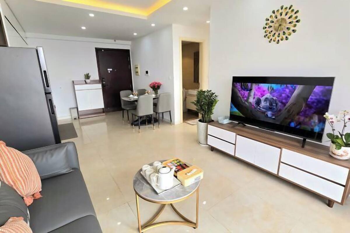 Un saló modern amb televisió de pantalla plana, un sofà, una taula de centre i una zona de menjador al fons.