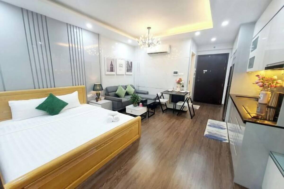 Habitació d'hotel amb un llit, un sofà, una taula petita, un escriptori i una cuineta.