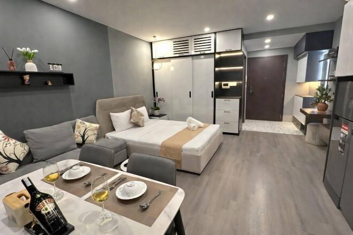 Habitació d'hotel moderna amb llit, zona de dinar, petita cuina i armari encastat.