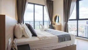 Ein modernes Hotelzimmer mit einem großen Bett, einem Nachttisch, einem Spiegel und Blick auf die Stadt durch große Fenster.