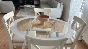A round glass table with white chairs, a woven placemat, and a brown bowl in the center. - Urban Luxury Apartment Zagreb  One  Bedroom Apartment (Zagreb)