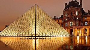Die Louvre-Pyramide mit ihrem Spiegelbild im Wasser, neben dem historischen Louvre-Palais.