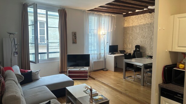Ein modernes Wohnzimmer mit einer Couch, einem Fernseher, einem Esstisch und einer Küchenzeile.