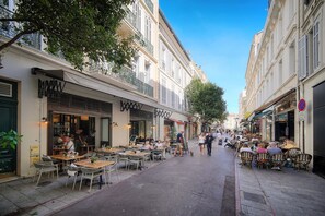 A narrow street lined with cafes and restaurants, outdoor seating, and pedestrians. - 2-Bedroom Apartment with Balcony in the Heart of Downtown A1B162 (Cannes)
