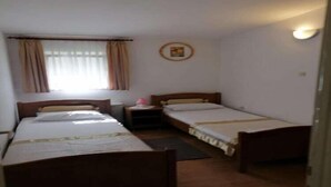 Una stanza con due letti singoli, un comodino, un tavolino e una finestra con tende.