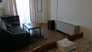 A living room with a sofa, a small table, a radiator, and a door. - Apartments Libertas - Studio with Balcony and Sea View - (3) (Rogoznica)