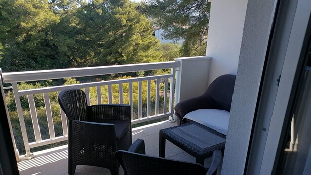A balcony with wicker furniture, a white railing, and a view of trees. - Apartments Libertas - Studio with Balcony and Sea View - (3) (Rogoznica)