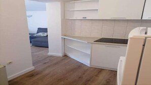 Eine kleine Küche mit weißen Schränken, einer Arbeitsplatte und einem Kühlschrank.