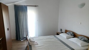 Ein Schlafzimmer mit Bett, Vorhängen, einem Nachttisch und einer Lampe.