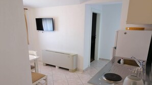 A compact kitchen with a built-in oven, a sink, and a television mounted on the wall. - Apartments Libertas - Two Bedroom Apartment with with Terrace and Sea View (7) (Rogoznica)