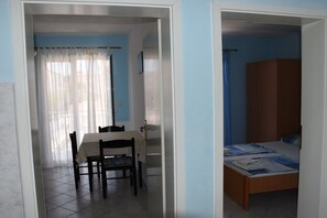 Une pièce avec un lit, une table et des chaises, et une fenêtre avec des rideaux.