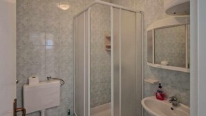 Un baño con ducha, inodoro, lavabo y un espejo sobre el lavabo.