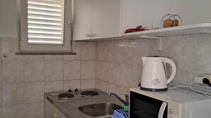 Una cocina compacta con microondas, hervidor y un lavabo pequeño.