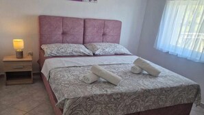 Una cama bien hecha con una colcha estampada, dos almohadas y dos toallas enrolladas.