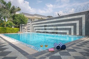 Ein Schwimmbecken mit Schachbrettmuster, zwei Gläser Weißwein und aufgerollte Handtücher.