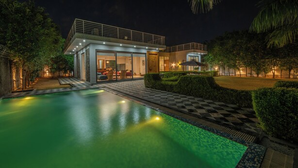 Une maison moderne dotée d’une piscine, d’un patio couvert et d’une entrée bien éclairée.