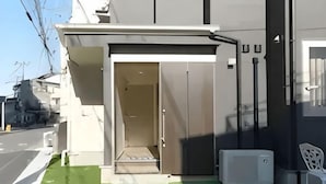 A building entrance with a door, a small step leading up, and a white chair outside. - Lumine Ikebukuro (Tokyo)