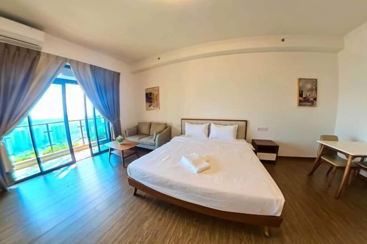 A hotel room with a large bed, a desk, a chair, a small table, and a view of the outdoors.