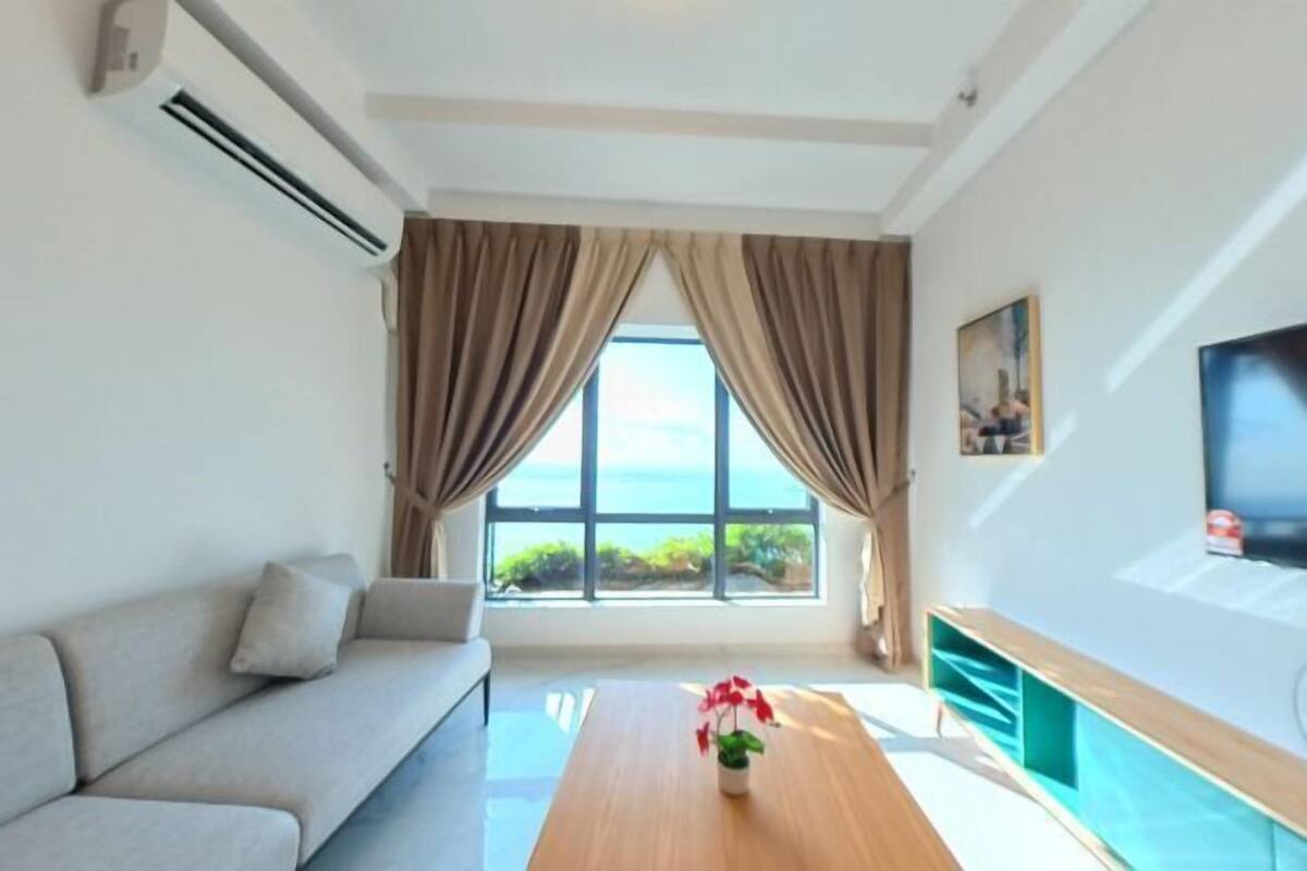 A modern living room with a sofa, a wooden coffee table, and a large window with curtains.
