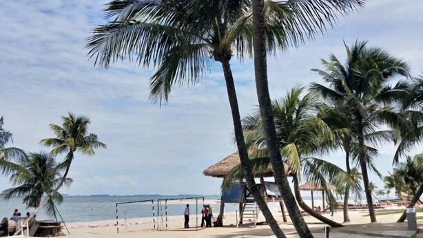 A beach with palm trees, a thatched-roof hut, and a volleyball net. - Forest City Carnelian Tower Summer Home Day Hotel（Infinity pool） (Gelang Patah)
