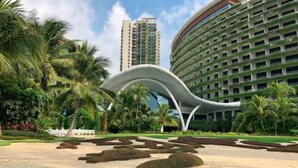 A modern hotel with a curved facade, surrounded by palm trees and a landscaped garden. - Forest City Carnelian Tower Summer Home Day Hotel（Infinity pool） (Gelang Patah)