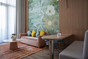 A modern living room with a sofa, round coffee table, and a bar stool. - KARAVANSARAY Turkistan Harbour Hotel - Free FLYING THEATRE Entrance (Turkistan)