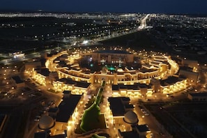 A circular building complex with multiple levels and a central courtyard, surrounded by roads and other buildings. - KARAVANSARAY Turkistan Harbour Hotel - Free FLYING THEATRE Entrance (Turkistan)