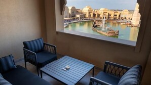 A balcony with two sofas and a table, overlooking a pool and buildings. - KARAVANSARAY Turkistan Harbour Hotel - Free FLYING THEATRE Entrance (Turkistan)