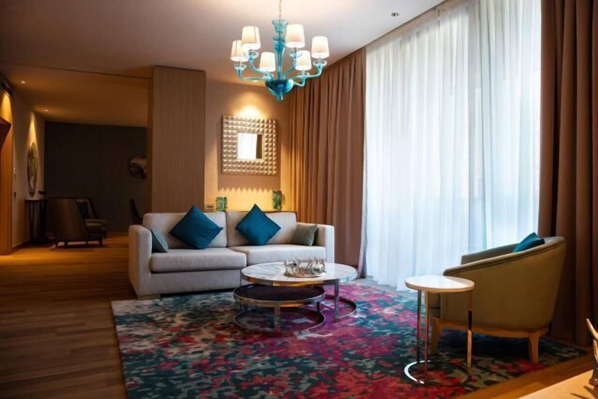 Ein modernes Wohnzimmer mit Sofa, Sessel, Couchtisch und einer Deckenleuchte.