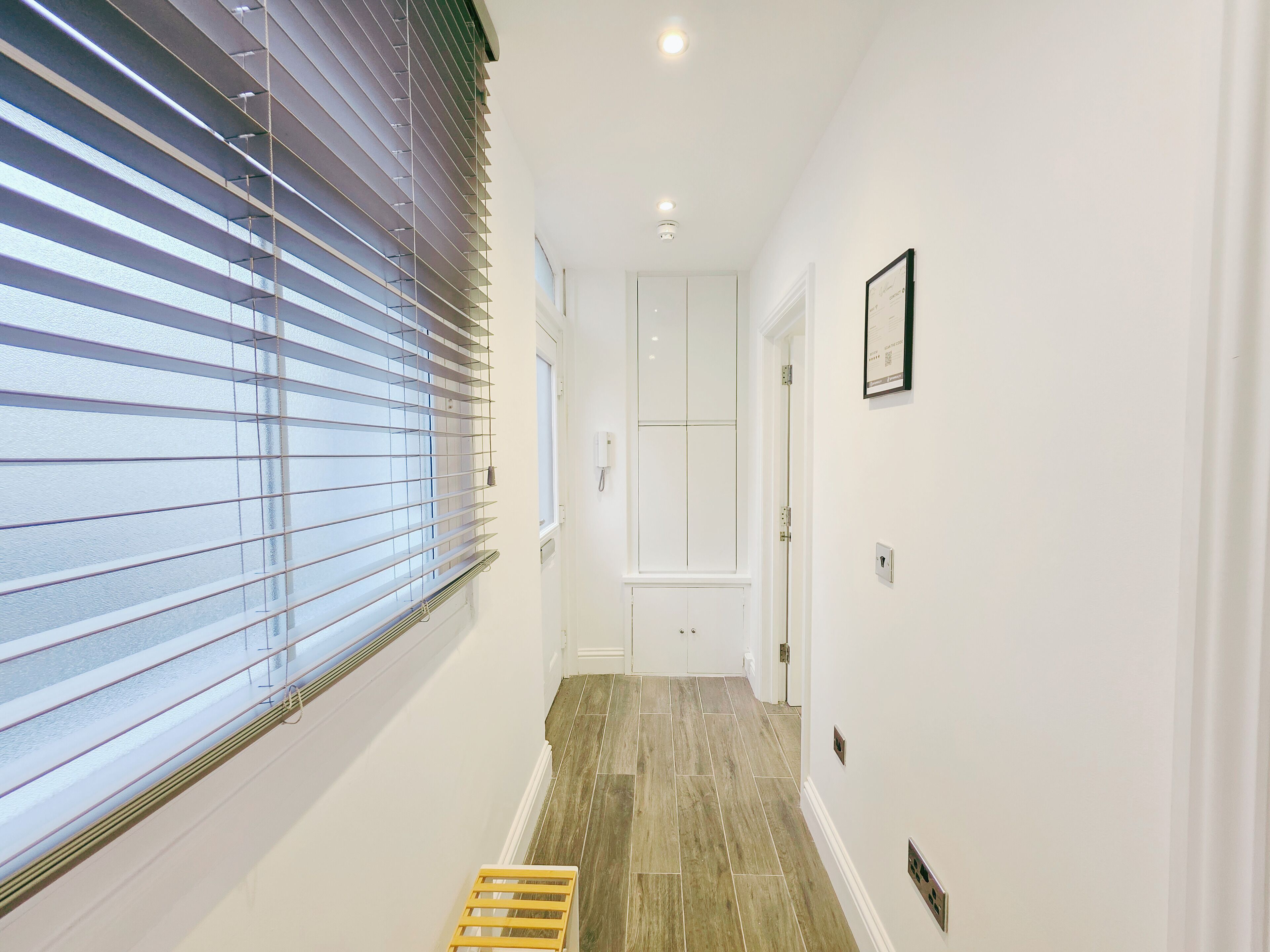 A hallway with a window, a door, and a small step leading to another room.