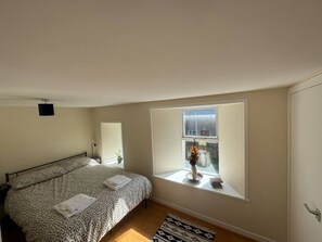 A bedroom with a bed, a window, a small table, and a potted plant. - Cosy House in the heart of Kirkwall (Kirkwall)