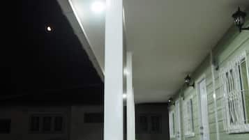 Een balkon met een hekwerk, een wit plafond en een raam met witte luiken.