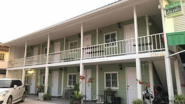 A two-story building with a balcony, potted plants, and a sign indicating a business. - Baan Wira Guesthouse (Khon Kaen)