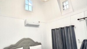 A bedroom with a bed, curtains, an air conditioning unit, and a window. - Baan Wira Guesthouse (Khon Kaen)