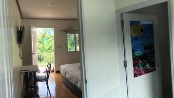 A room with a bed, a desk, a chair, a window, and a door with an underwater scene.