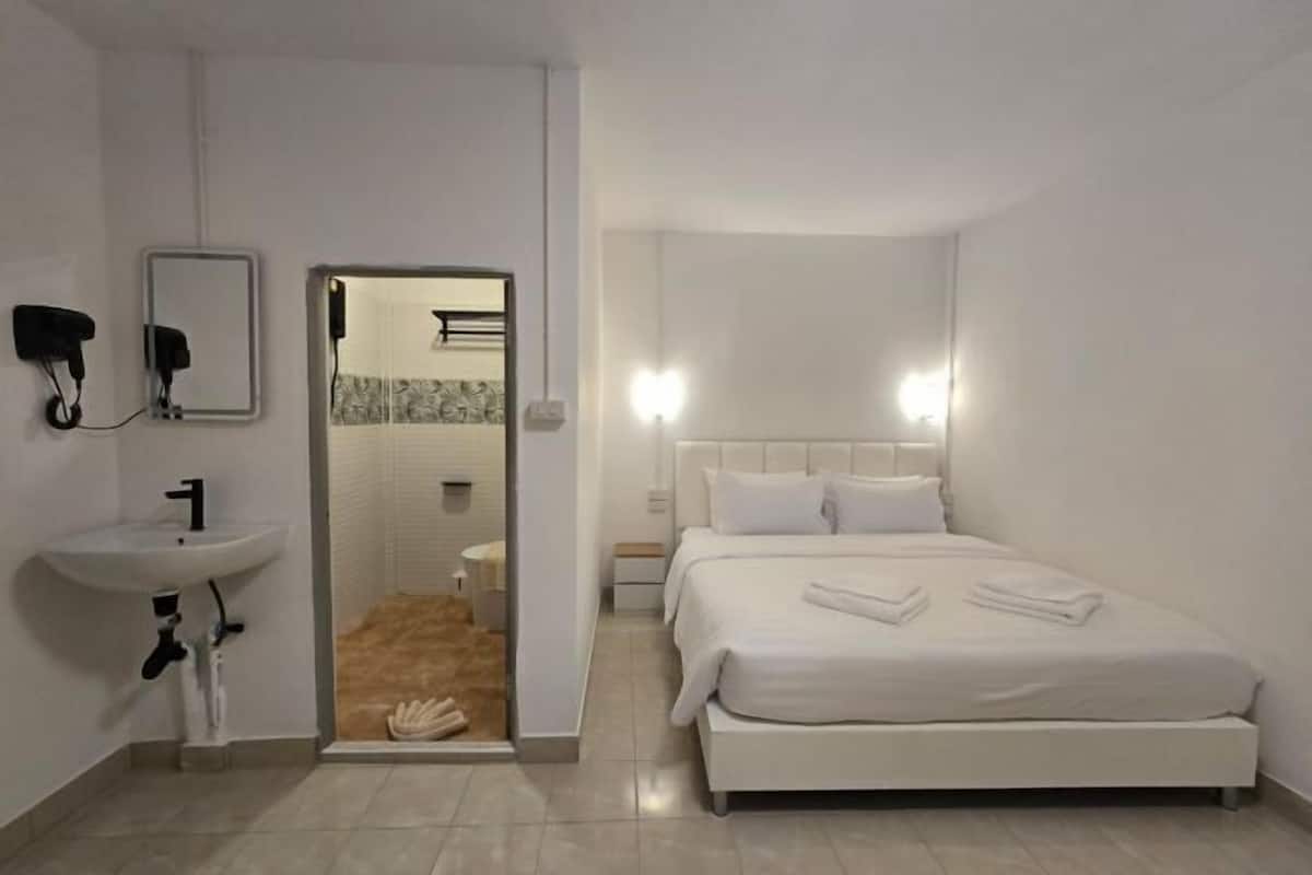 Une chambre d’hôtel comprenant un lit, un lavabo, un miroir et une porte donnant sur une salle de bain.