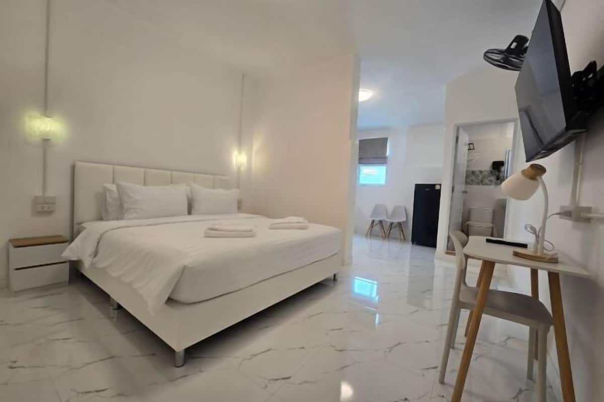 Une chambre d’hôtel moderne dotée d’un grand lit, de tables de chevet, d’un bureau et d’un téléviseur à écran plat.