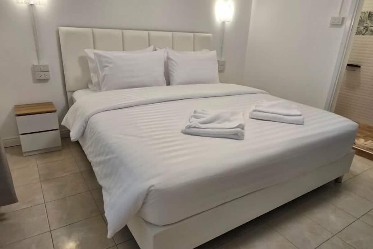 Un lit bien fait, avec des draps blancs et deux serviettes pliées posées sur le lit.