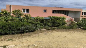 Um edifício moderno com telhado plano, fachada rosa e uma janela pequena.