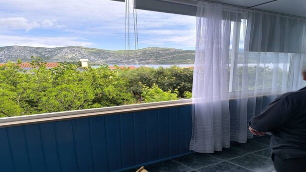 Quarto com vista para uma paisagem montanhosa através de cortinas translúcidas.