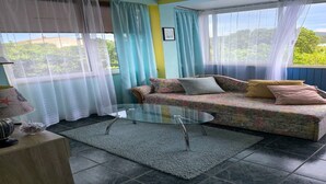 Quarto com sofá, mesa de centro de vidro e cortinas.