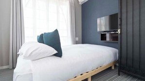 A hotel room with a bed, a TV mounted on the wall, and a window with curtains. - CONTEL Meidaimae (Tokyo)