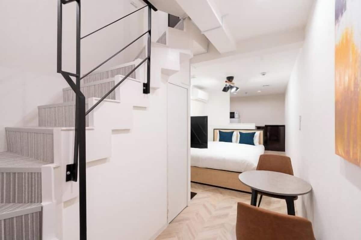 Une chambre d’hôtel moderne avec un escalier, un lit avec des oreillers, une petite table et une chaise.