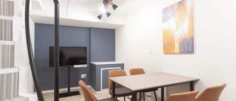 Una habitación moderna con una mesa de comedor, sillas, un televisor y un cuadro en la pared.