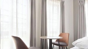 A hotel room with a bed, a round table, two chairs, and a window with curtains. - CONTEL Meidaimae (Tokyo)